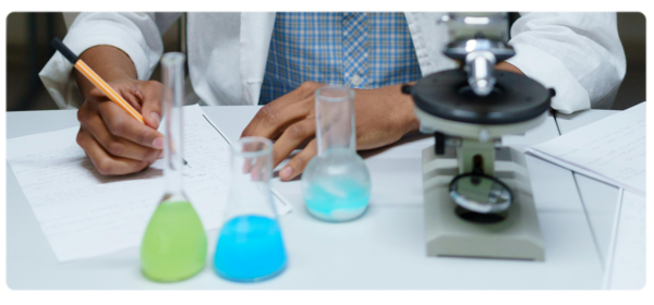 biophysicist writs on paper with colored beakers in foreground