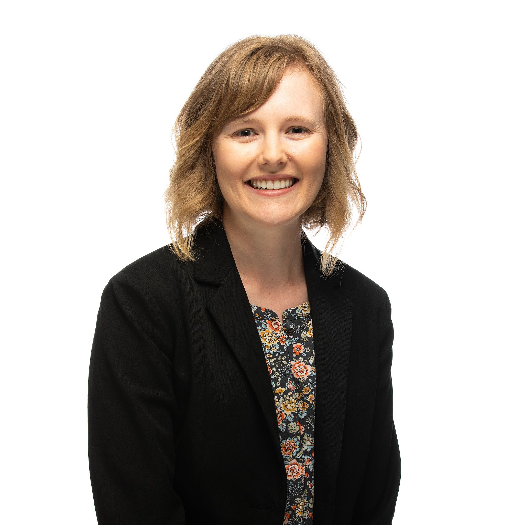 Smiling, blond woman in black sweater with black and white shirt.