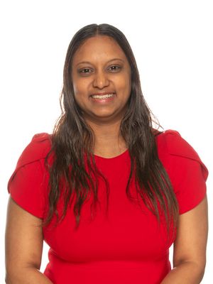Amanda Ramoutar stands in front of a white background, she smiles towards the camera.