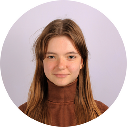 Close-up headshot of tutor Anna wearing a turtleneck and standing in front of a lavender wall.