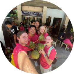 A student missionary is taking a selfie with a group. They are all holding fruit in their hands.