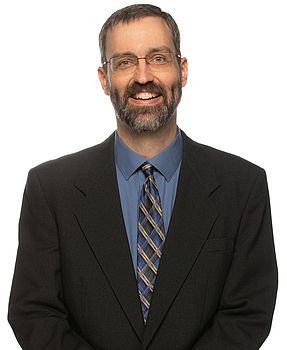 Headshot photo of Eric James standing in front of a white background.