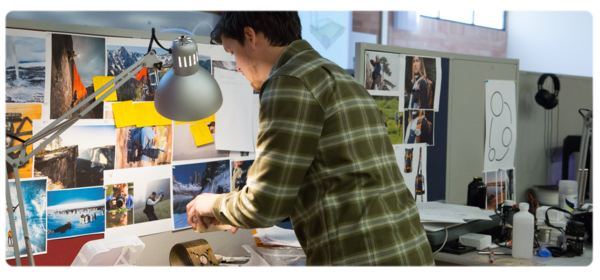 A product design student works at a lab workstation covered in colorful inspiration photos