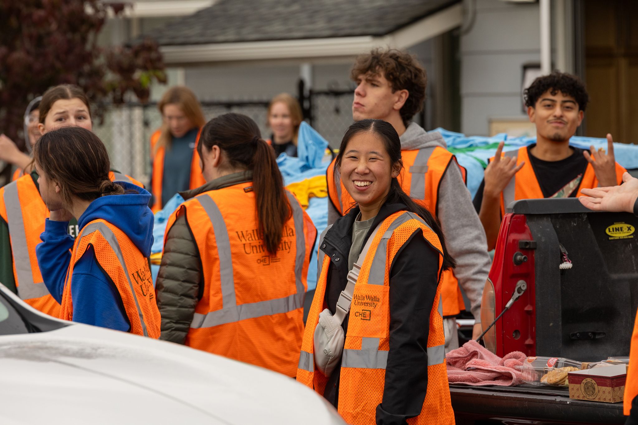 Girl with orange vest on smiles brightly as she gets ready to begin the day.