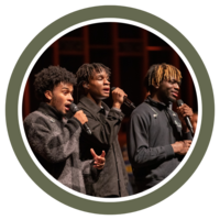 Photo of three students on stage at the WWU Church singing into microphones