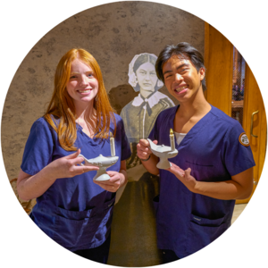 2 students smile at the camera next to a cardboard cutout