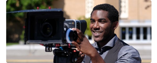 A student films using a film camera.