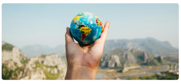 A hand holds a small globe