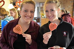 Two girls with heart shaped waffles at residence hall Valentine's day celebration