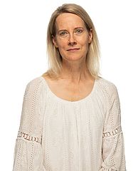 Karlyn Bond stands in front of a white background. She is smiling toward the camera.