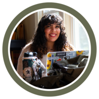 Photo of a student smiling at The Atlas with her laptop and water bottle on a table