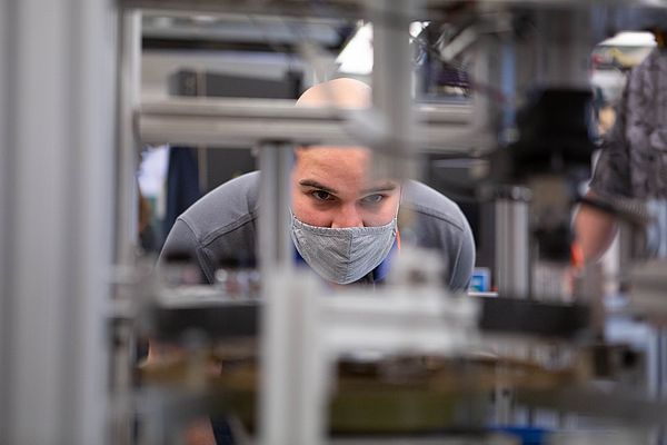 Student watching their manufacturing robot operate..