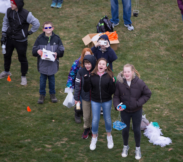 Elementary school students watch the action from the ground below.