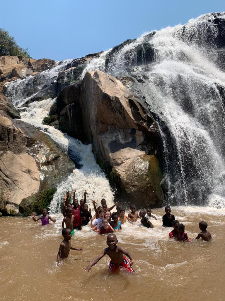 Madelyn and a group of children play in a waterfall